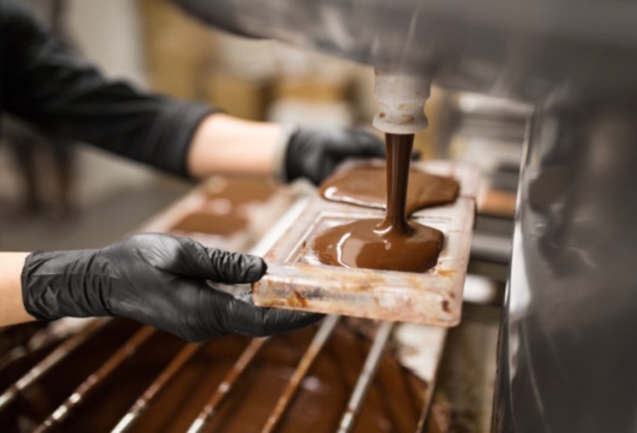 A machine filling chocolate moulds