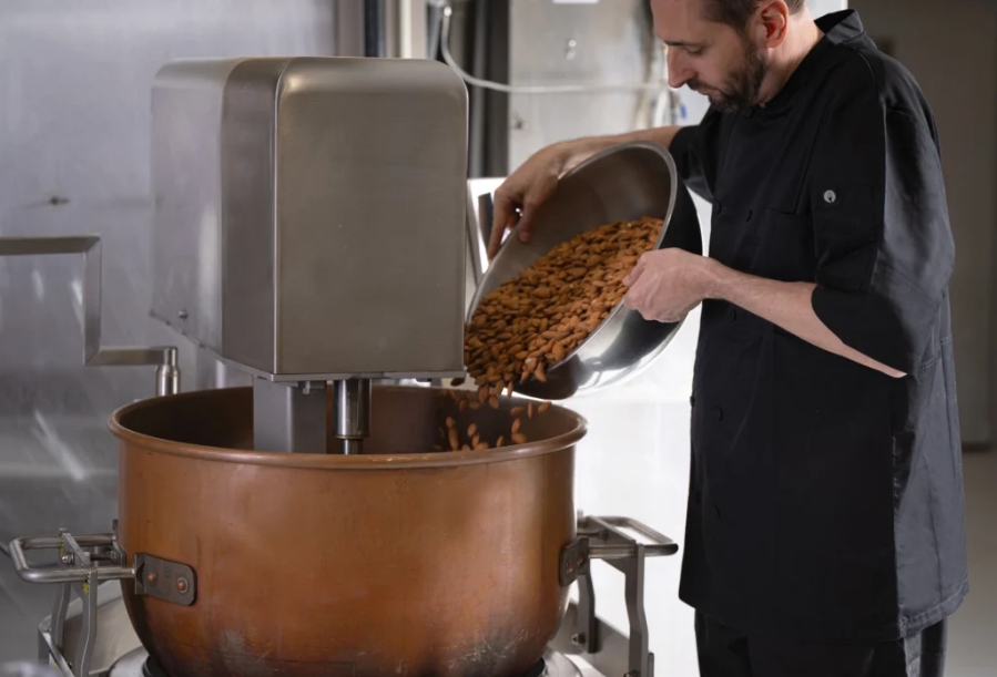 A man pouring cocoa beans into a mixer